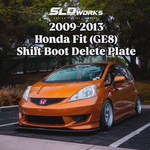 May include: An orange Honda Fit (GE8) car with a Shift Boot Delete Plate. The car is parked on a paved surface. The text on the image reads "SLO WORKS DESIGN PRINT INSPIRE" and "2009-2013 Honda Fit (GE8) Shift Boot Delete Plate."