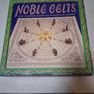 Puede incluir: Una caja de juego de mesa titulada "Noble Celts: The Classic Game of Circular Chess". La caja presenta un borde verde con diseños de nudos celtas. El tablero de juego es visible, con piezas marrones y blancas dispuestas en un patrón circular.