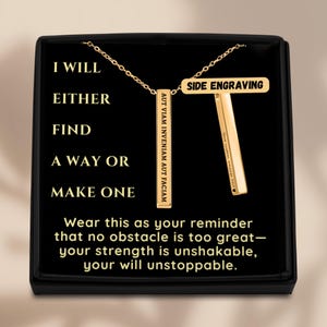May include: Gold-colored bar pendant necklace with a chain, displayed in a black box. The pendant has the text "AUT VIAM INVENIAM AUT FACIAM" and "SIDE ENGRAVING". The box has the text "I WILL EITHER FIND A WAY OR MAKE ONE".