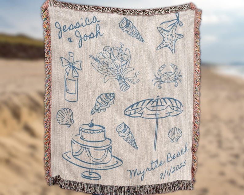 Person holding a custom beach wedding blanket with hand drawn coastal icons including starfish, seashells, champagne glasses, bouquet, umbrella, and wedding cake, displayed against a blurred beach background. Personalized names and date design make it a unique coastal wedding gift, destination wedding keepsake, or custom couple anniversary present.