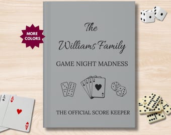 Puede incluir: Cubierta gris con el texto "The Williams Family Game Night Madness The Official Score Keeper" con imágenes de cartas de juego, fichas de dominó y dados.