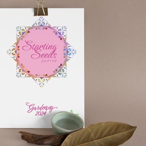 May include: A white journal with a pink circle and the text "Starting Seeds Journal" in a decorative font. The circle is surrounded by a colorful floral design. The text "Gardening 2024" is written in pink below the circle.