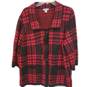 May include: Red and black plaid cardigan with a button-up front and two front pockets. The cardigan has a shawl collar and three-quarter sleeves. The fabric has a woven texture.