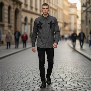 May include: A charcoal grey long-sleeved button-down shirt featuring black embroidered cross designs on the chest, paired with slim-fit black trousers and black leather shoes. The shirt has a classic collar and a full-length button placket.