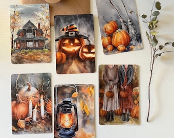 May include: Set of six Halloween-themed art cards featuring watercolor illustrations. The cards depict a haunted house, jack-o'-lanterns, pumpkins, a lantern, a broom, and two figures holding pumpkins. The color palette includes orange, brown, and gray.