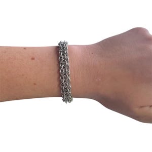 May include: A silver chain bracelet with multiple rows of links.