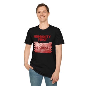 Peut inclure: T-shirt noir avec le texte rouge "HUMANITY FIRST" au-dessus d'un motif de mur de briques avec les mots "NO ICEHOLES". Le t-shirt est à col rond.
