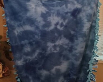 May include: A blue and white tie-dye fleece blanket with a light blue fringe border.