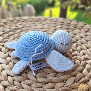 Peut inclure: Un jouet en crochet en forme de tortue bleu et blanc avec une étiquette indiquant "Fait main avec amour".