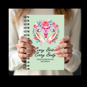 May include: A spiral-bound notebook with a light green cover. The cover features a pink uterus illustration surrounded by flowers and hands. The text reads "Every Birth, Every Body, Empowering Women."