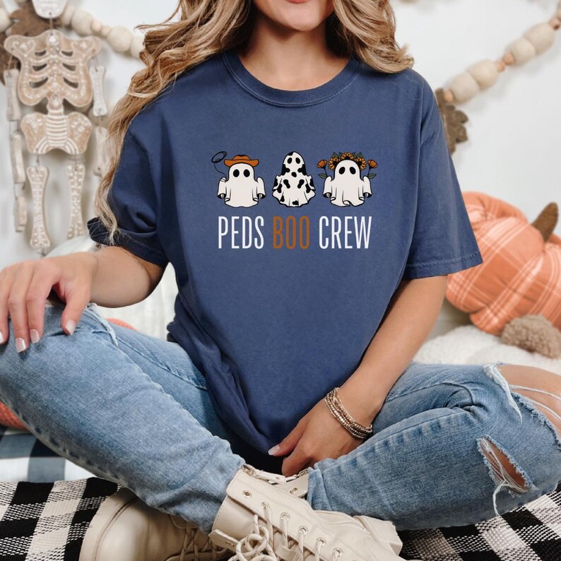 Puede incluir: Una camiseta azul marino con un gr&aacute;fico de tres fantasmas con diferentes disfraces. El texto "PEDS BOO CREW" est&aacute; impreso debajo de los fantasmas.