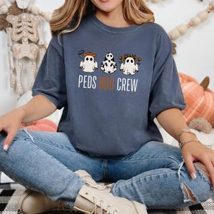 Puede incluir: Una camiseta azul marino con un gr&aacute;fico de tres fantasmas con disfraces. El texto "PEDS BOO CREW" est&aacute; impreso debajo de los fantasmas.