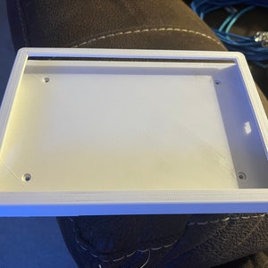 May include: A white plastic frame with a smooth surface and rounded edges. There are three small holes on the frame.