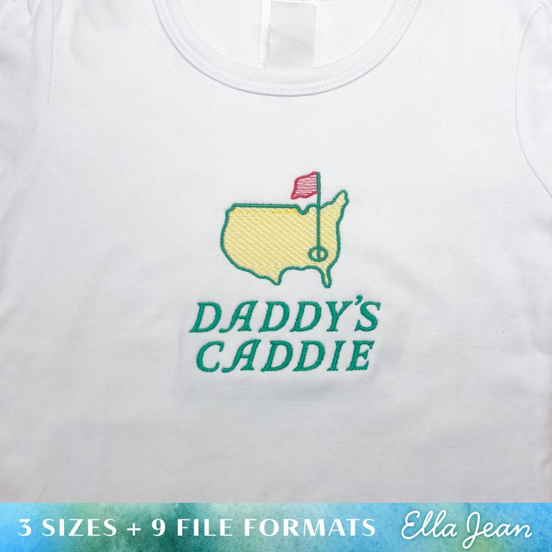 May include: White t-shirt with green embroidery of a golf course and the text "Daddy's Caddie".