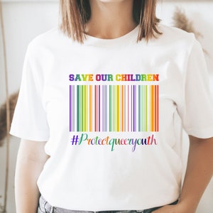May include: White t-shirt with the text "SAVE OUR CHILDREN" and a rainbow barcode underneath. The text "#ProtectQueerYouth" is below the barcode.