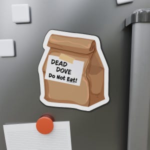 May include: A brown paper lunch bag magnet with the text "DEAD DOVE Do Not Eat!" on a white label, secured with tape. The magnet is on a gray refrigerator door, with other magnets visible.