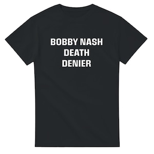 Può includere: Maglietta nera con testo bianco che recita "BOBBY NASH DEATH DENIER"