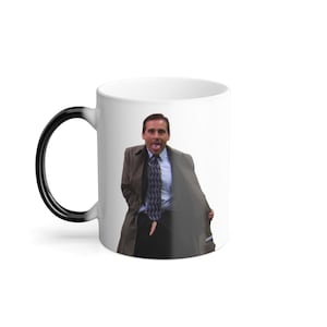 May include: White ceramic mug with a black handle that transitions to white. The mug features a color image of a man in a suit and tie, wearing a trench coat. The man is sticking out his tongue.