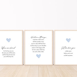 May include: Three light blue watercolor heart prints with inspirational text. The first print says "You are loved for the boy you are, the man you will become, and for the precious son you will always be." The second print says "Hold him a little longer, rock him a little more, tell him another story (you've only told him four), let him sleep on your shoulder, rejoice in his happy smile, for he is only a little boy for such a little while." The third print says "Let me love you a little more before you're not so little anymore."