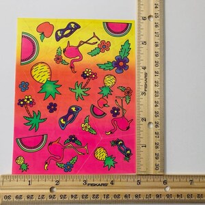May include: A sheet of colorful stickers featuring pink flamingos, pineapples, watermelon slices, sunglasses, and flowers on a pink, orange, and yellow gradient background.