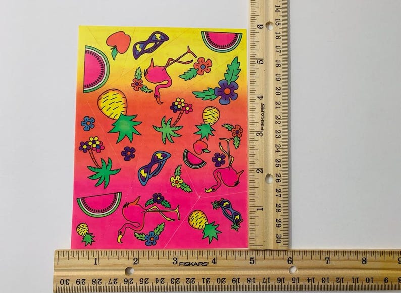 May include: A sheet of colorful stickers featuring pink flamingos, pineapples, watermelon slices, sunglasses, and flowers on a pink, orange, and yellow gradient background.