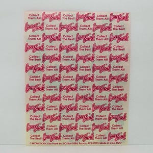 May include: A sheet of pink and white stickers with the text "Lisa Frank" and "Collect Them All!" repeated multiple times. The stickers are on a white background.