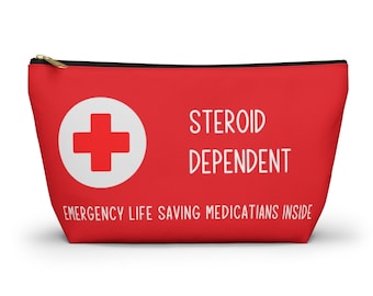 Op de afbeelding: Rode ritszak met een wit kruis en de tekst "STEROID DEPENDENT EMERGENCY LIFE SAVING MEDICATIONS INSIDE".