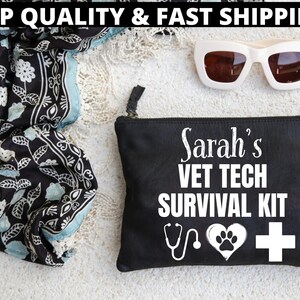 Op de afbeelding: Zwarte etui met ritssluiting met de tekst "Sarah's VET TECH SURVIVAL KIT" in het wit. Het ontwerp omvat een stethoscoop, een hart met pootafdruk en een wit kruis. Ook een zwart-witte bloemen sjaal en een witte zonnebril.