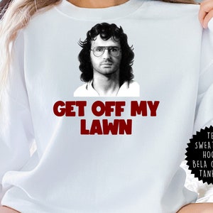 Può includere: Felpa bianca con un'immagine in bianco e nero di un uomo con gli occhiali e la scritta rossa "GET OFF MY LAWN". Un'etichetta nera sul lato recita "TEES, SWEATSHIRT, HOODIE, BELA CANVAS, TANK TOP".