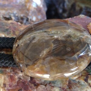 Pu&ograve; includere: Un bolo tie in agata marrone e trasparente con un cordoncino nero. L'agata &egrave; lucidata e presenta un motivo naturale.