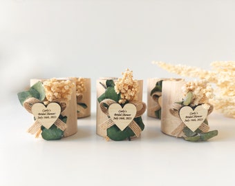 May include: Four small wooden boxes with dried flowers and a heart-shaped tag that says "Carly's Bridal Shower July 16th, 2023".