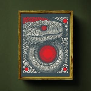 Può includere: Stampa artistica incorniciata con un'illustrazione dettagliata di un serpente. L'opera è principalmente in bianco e nero con accenti rossi, tra cui l'occhio del serpente e un grande cerchio centrale. La cornice è color legno naturale.