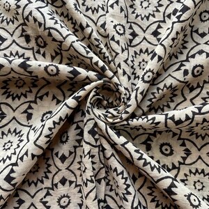 May include: A beige fabric with a black and white geometric pattern. The fabric is folded and has a soft, textured feel.