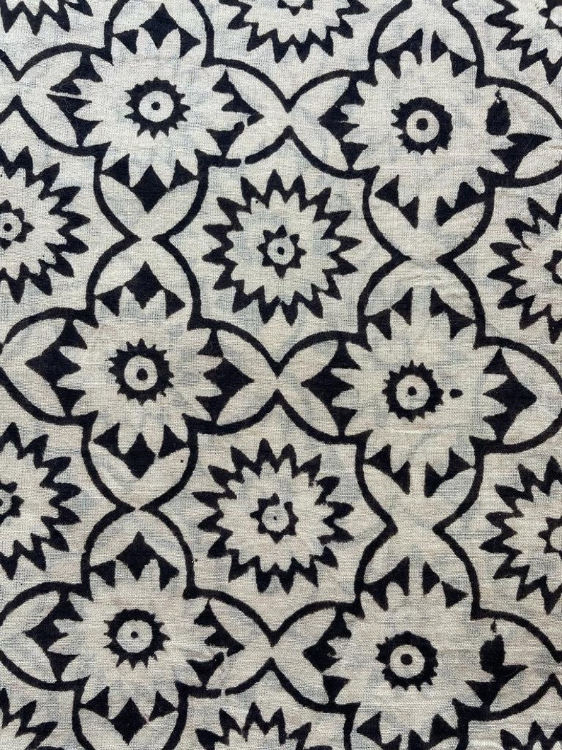 May include: Black and white fabric with a repeating pattern of stylized flowers. The flowers have a central circle and radiating points.