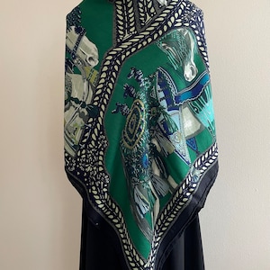 Peut inclure: Un foulard en soie vert avec un motif &eacute;quin. Le foulard pr&eacute;sente un fond vert fonc&eacute; avec des accents blancs, bleus et dor&eacute;s. La bordure est bleu marine fonc&eacute; avec un motif de feuilles blanches. Le foulard est drap&eacute; sur un mannequin noir.