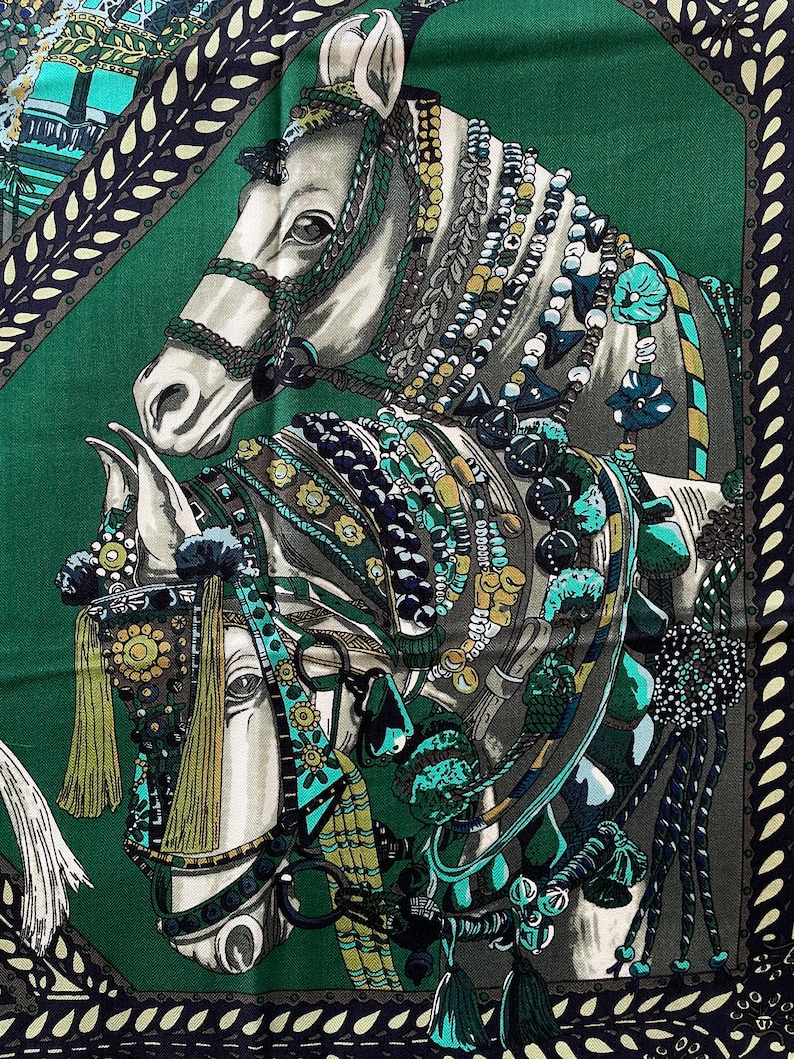 Peut inclure: Foulard carr&eacute; en soie repr&eacute;sentant deux chevaux blancs orn&eacute;s d'une sellerie color&eacute;e et de perles. Les chevaux se d&eacute;tachent sur un fond vert fonc&eacute; avec une bordure d&eacute;corative dans les tons de turquoise, marine et cr&egrave;me.
