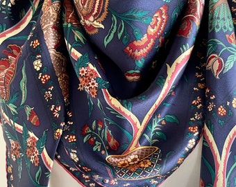 May include: A navy blue silk scarf with a floral pattern. The pattern features red, green, and brown flowers and leaves. The scarf has a pink border.