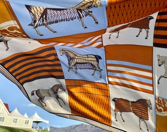 May include: A colorful silk scarf with a repeating pattern of horses in various poses. The scarf is in shades of brown, orange, blue, and white.