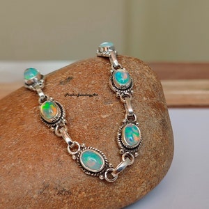 Peut inclure: Un bracelet en argent avec des pierres d'opale de forme ovale. Le bracelet a un design de chaîne délicat et est accentué de petites perles d'argent.