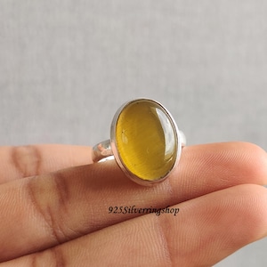 May include: A silver ring featuring a large, oval yellow gemstone. The ring has a plain band and a bezel setting. The text "925Silverringshop" is visible at the bottom of the image.