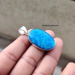 May include: A silver pendant featuring a large oval blue opal gemstone. The opal has a shimmering, iridescent effect.