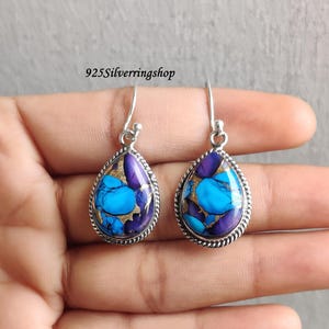 Puede incluir: Pendientes en forma de lágrima con marco plateado. Presentan un mosaico de piedras azules, moradas y doradas. El texto "925Silverringshop" es visible en la imagen.