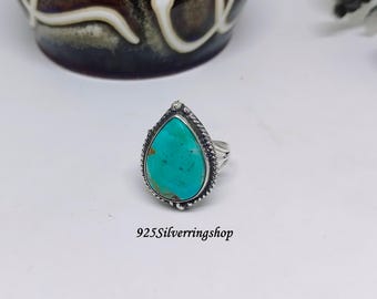 May include: A turquoise teardrop-shaped ring set in sterling silver. The ring has a delicate, twisted band and a smooth, polished finish.