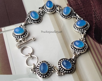 May include: A silver bracelet with blue gemstone accents. The bracelet has a toggle clasp and is adorned with small beads.