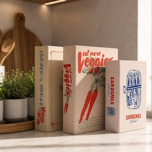 Könnte beinhalten: Drei rechteckige Dekoboxen mit cremefarbener Oberfläche. Die erste Box zeigt den roten Schriftzug FARMER'S MARKET und eine Tomate. Die zweite zeigt den roten Text eat more Veggies und Karotten. Die dritte zeigt blaue Sardinenillustrationen und den roten Text SARDINES Portugal.