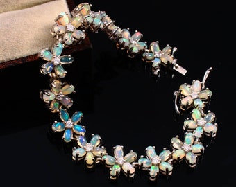May include: A silver bracelet with a floral design featuring iridescent opal gemstones. The bracelet is made up of a series of flower-shaped links, each with a central opal surrounded by smaller diamonds.