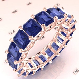 Könnte beinhalten: Ein Ewigkeitsring aus Roségold mit einer Reihe blauer Smaragdschliff-Edelsteine.