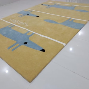 May include: A yellow rug with a repeating pattern of blue fox silhouettes. The rug has white stripes running horizontally across the surface.