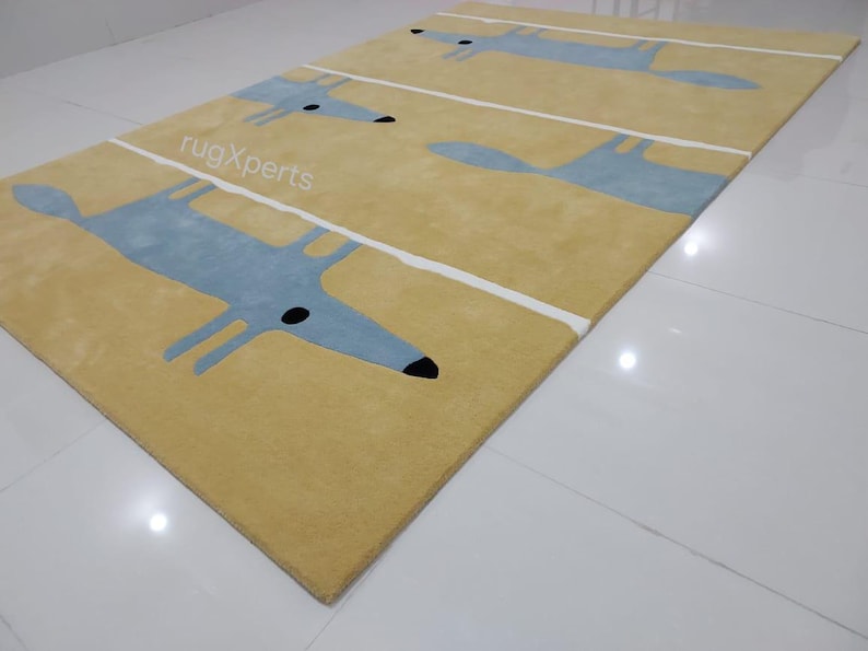 May include: A yellow rug with a repeating pattern of blue fox silhouettes. The rug has white stripes running horizontally across the surface.