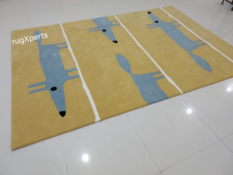 May include: A yellow rug with a blue and white fox design. The rug has a modern, minimalist style.